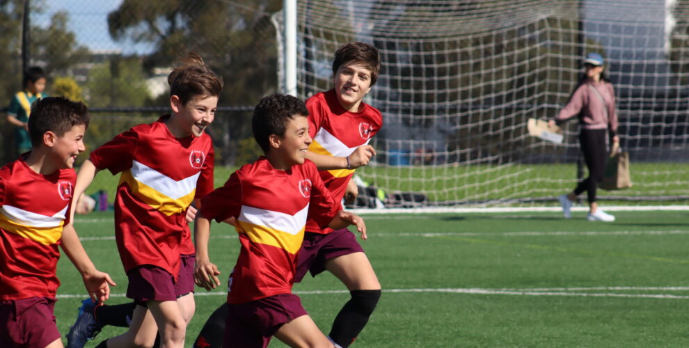 Kids running on soccer field smiling
